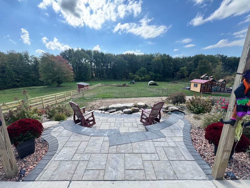 Scenic outdoor patio with chairs, gardens, and rural landscape featuring animals and playground.